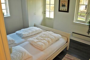 A bedroom with two beds, a window, a door, and a framed picture on the wall. - Holiday home just 400 meters from the water (Rudkøbing)