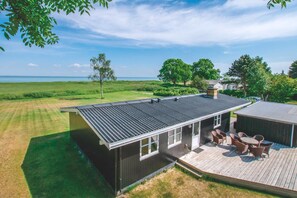 A modern house with a deck, a chimney, and a view of the sea.