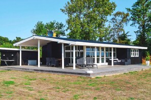 A modern building with a covered patio area, outdoor seating, and a large windowed section.