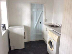 A compact laundry room with a washing machine, a dryer, and a sink. - Lovely apartment directly opposite the harbor (Rudkøbing)