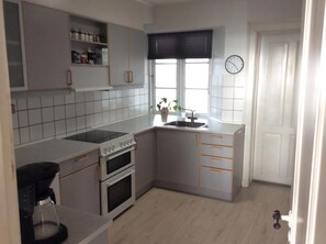A compact kitchen with a stove, oven, sink, and cabinets. - Lovely apartment directly opposite the harbor (Rudkøbing)