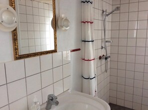 A bathroom with a sink, mirror, and shower. - Lovely apartment directly opposite the harbor (Rudkøbing)