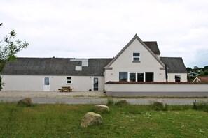 A two-story building with a white exterior, a pitched roof, and a small porch area. - Holiday home for up to 12 pople with sea view (Rudkøbing)