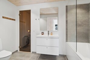 Ein Badezimmer mit Toilette, einem Waschbecken mit Spiegel und einer Badewanne.