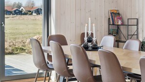A dining area with a table, chairs, candles, and a bookshelf. - Modern holiday home with spa for 10 people (Væggerløse)