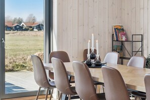 A dining area with a table, chairs, candles, and a bookshelf. - Modern holiday home with spa for 10 people (Væggerløse)