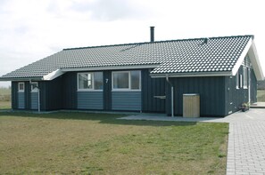 Een gelijkvloers gebouw met een pannendak, een voordeur en een kleine aangebouwde garage.