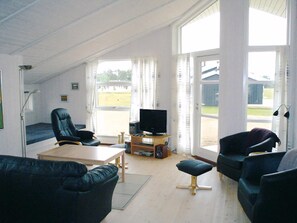 A spacious living room with a high ceiling, a television, a wooden table, and a sofa. - holiday home only 400 meters from the water (Rudkøbing)
