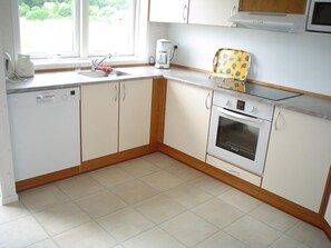 A kitchen with white cabinets, a built-in oven, a coffee maker, and a window. - holiday home only 400 meters from the water (Rudkøbing)