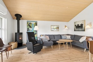 A modern living room with a fireplace, a sofa set, a coffee table, and a wooden ceiling. - Lovely holiday home at Kongsmark Strand (Slagelse)