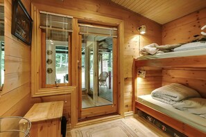 A wooden cabin room with a bunk bed, a small table, a chair, and a window with blinds. - Charming vacation home on large grounds (Rudkøbing)