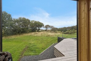 Una terraza de madera con vista a un campo cubierto de césped y árboles.