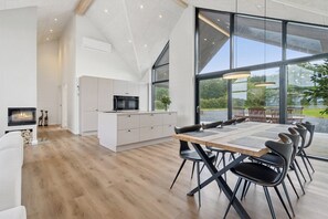 A modern kitchen with a built-in oven and microwave, a dining area with a large table and chairs, and a fireplace.
