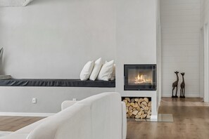 Una sala moderna con chimenea, un banco con cojines y un sofá.