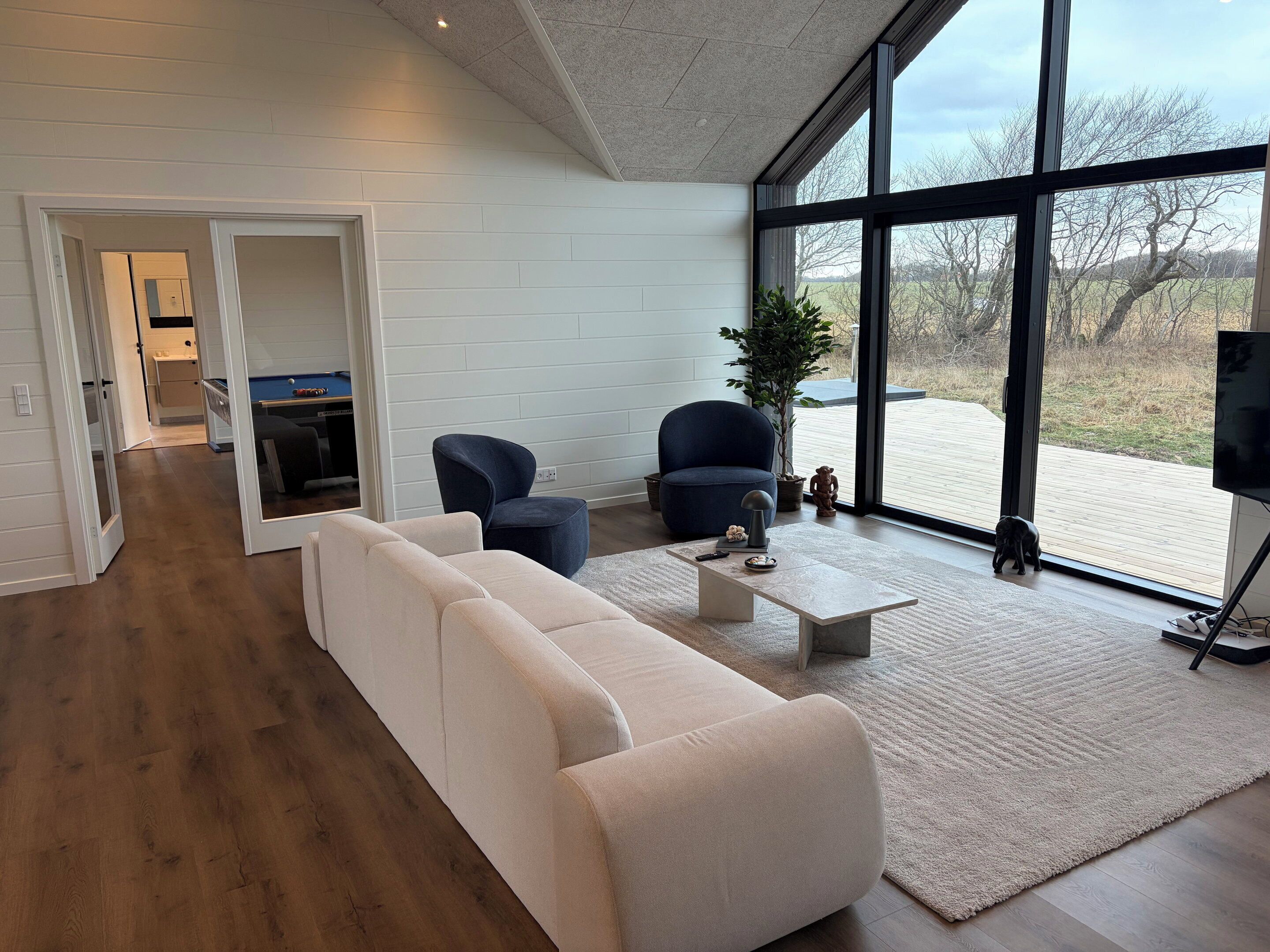 Una sala de estar moderna con un sofá, sillones, una mesa de centro y un televisor.
