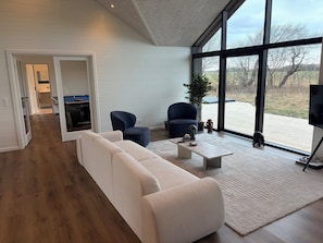 Ein modernes Wohnzimmer mit einer Couch, Sesseln, einem Couchtisch und einem Fernseher.