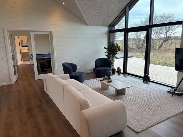 A modern living room with a sofa, armchairs, a coffee table, and a TV.