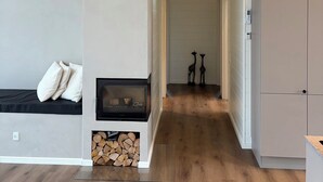 Un interior modern amb una llar de foc, una zona de cuina i un passadís que condueix a una altra habitació.