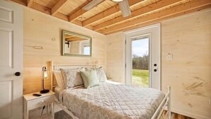 A bedroom with a bed, bedside table, lamp, mirror, and a door leading to a balcony. - Special Retreat in Nancy (Faubush)