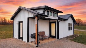 A single-story building with a covered porch, a grill, and a chair. - Special Retreat in Nancy (Faubush)