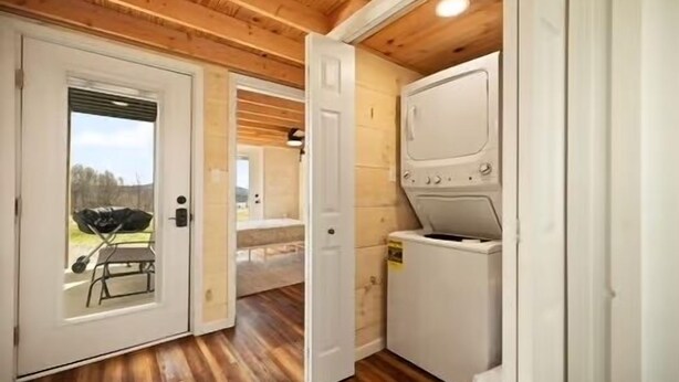 A laundry room with a washing machine, wooden floors, and a door leading to an outdoor area with a barbecue grill. - Special Retreat in Nancy (Faubush)