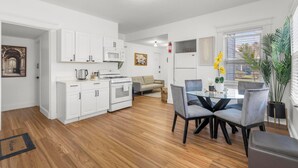 A modern kitchen with white cabinets, a microwave, and a stove. There is a dining area with a glass table and chairs. - Relaxing 3-bedroom apartment in New Haven (New Haven)
