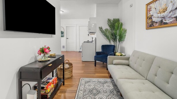 A modern living room with a flat-screen TV, a sofa, a blue chair, and a large potted plant. - Relaxing 3-bedroom apartment in New Haven (New Haven)