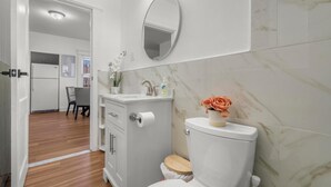 A bathroom with a toilet, sink, mirror, and marble walls. - Relaxing 3-bedroom apartment in New Haven (New Haven)