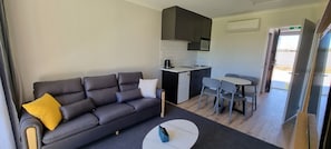 Una sala moderna con un sofá, una mesa de centro y un comedor con sillas y una mesa.