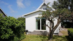 Una casa pequeña y blanca de una sola planta, con techo inclinado y chimenea.