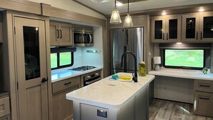 A modern kitchen with stainless steel appliances, a central island, and pendant lighting.