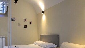 A hotel room with a bed, a chair, a radiator, and a wall-mounted light fixture. - Old town apartment, new and cozy (Napoli)