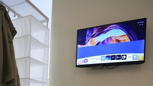 A hotel room with a bed, a television mounted on the wall, and two remote controls on the bed. - Old town apartment, new and cozy (Napoli)