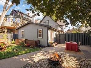 A backyard with a fire pit, a wooden bench, and a table set for dining. - 5BR home* Minutes to DT, Venues & Breweries (Minneapolis)