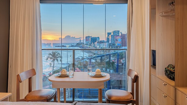 Ein Balkon mit Blick auf die Stadt, ein Tisch mit Stühlen und ein Holzschrank.