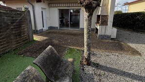 Een huis met een terras, een barbecueplek en een kleine tuin.
