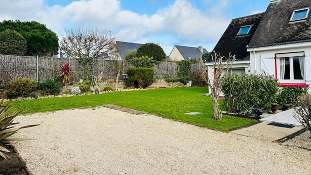 A residential property with a well-maintained lawn, a gravel driveway, and a stone wall. - Maison tout confort, proche plage et centre-ville (QUIBERON)