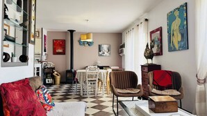 A living room with a checkered floor, a dining area with a table and chairs, and a kitchen in the background. - Maison tout confort, proche plage et centre-ville (QUIBERON)