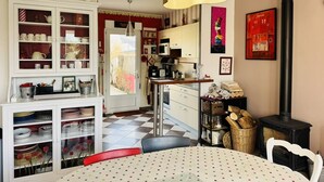 A cozy kitchen with a dining area, featuring a stove, cabinets, and a dining table with a polka dot tablecloth. - Maison tout confort, proche plage et centre-ville (QUIBERON)