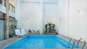 An indoor swimming pool with lounge chairs and a small table. - HOTEL PAIRUMANI (Cochabamba)