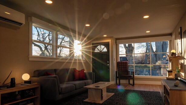 A modern living room with a sofa, coffee table, and a chair near large windows. - Restored 2BR Historic Cottage w/ Mesa Views – Grand Junction (Grand Junction)