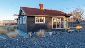 A rustic cabin with a metal roof, large windows, and a stone foundation. - Restored 2BR Historic Cottage w/ Mesa Views – Grand Junction (Grand Junction)