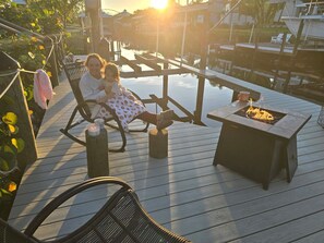 Ein Paar sitzt auf einer Holzterrasse mit einem Feuerkorb und Blick auf eine Marina.
