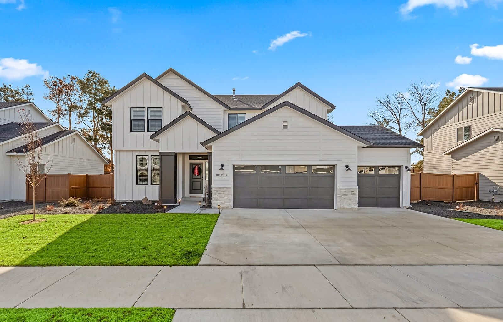 A modern two-story house with a garage, a well-maintained lawn, and a clear sky.