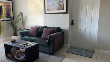 A living room with a ceiling fan, a couch, a coffee table, and a door.