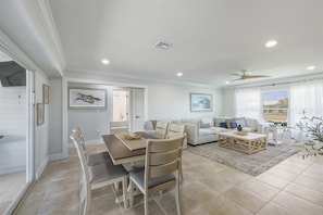 A spacious living area with a dining table, chairs, a sofa, and a coffee table. There is a ceiling fan, a window with curtains, and artwork on the walls. - Punta Gorda Isles 3 Bedroom Pool Home on Canal (Punta Gorda)
