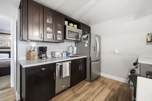 A modern kitchen with dark cabinets, stainless steel appliances, and a wooden floor. - Park City Ski Condo Walk to Slopes and Main Street (Park City)