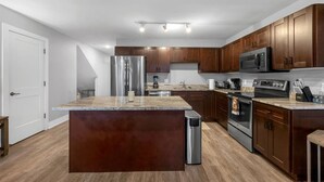 A modern kitchen with wooden cabinets, stainless steel appliances, and a marble countertop. - Serene Birmingham Retreat (Birmingham)