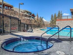 A swimming pool area with a hot tub, a separate pool, and a stone wall.