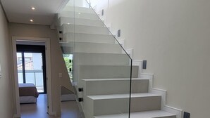 A modern staircase with glass railings leading to a bedroom. - Tranquil 3 Suite Home With Ocean Breeze in Prime Location! (Florianópolis)